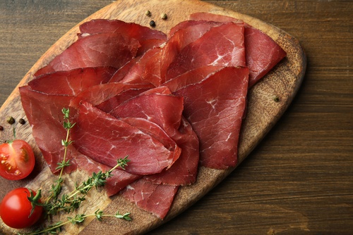fette di bresaola su un tagliere con pomodorini e timo min